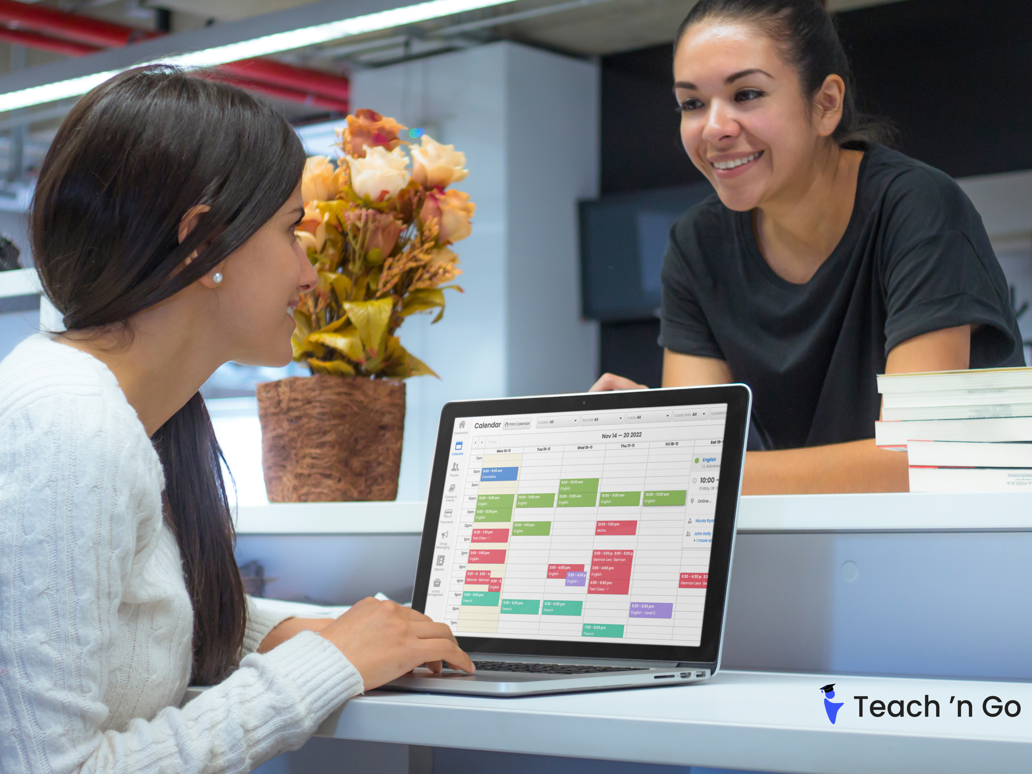 School administrator using a laptop to manage teacher schedules in a classroom.